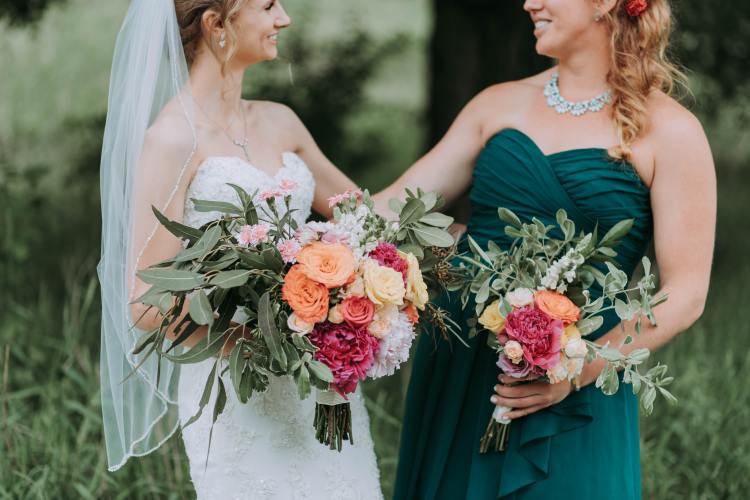 Rooted Weddings | Intimate  Package | Bride with flowers smiling at bridesmaid with flowers- Photo by Samantha Gades from Unsplash