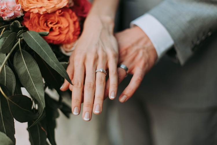 Rooted Weddings | Elopement Package | close up of groom and bride hands with wedding rings - Photo by Samantha Gades from Unsplash