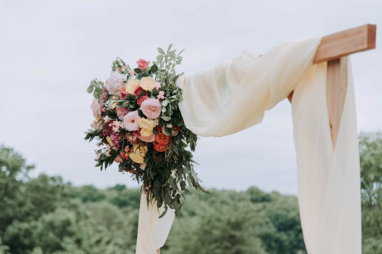 Rooted Weddings | Eloquent Package | Wood archway with fabric and flowers - Photo by Samantha Gades from Unsplash
